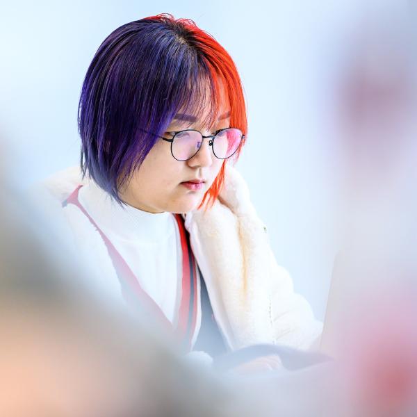 A student with a focused look against a blurred white background.